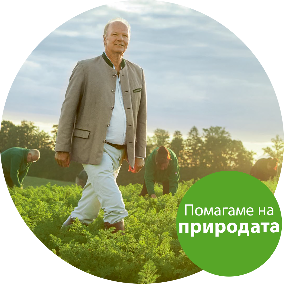 Възрастен мъж със светло сако и бели панталони върви през тучно зелено поле, а на заден план се виждат двама наведени.
