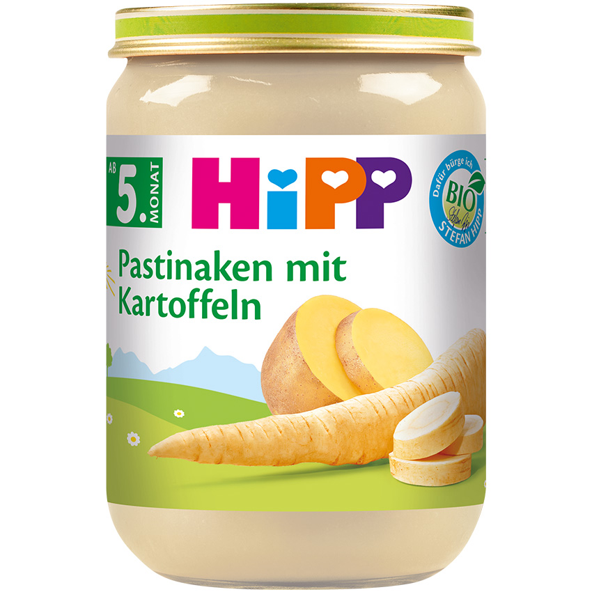 В стъклен буркан с етикет "HiPP" и биосертификат, съдържащ бежова паста, е изобразен пащърнак и нарязан картоф на зелено поле със синьо небе и бели облаци.