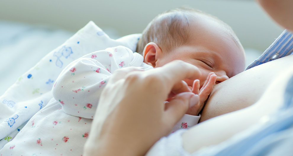 A close-up of a newborn baby being fed by a caregiver.