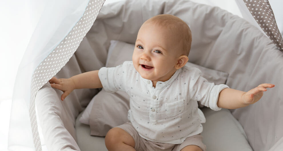 A baby sits in a bassinet.