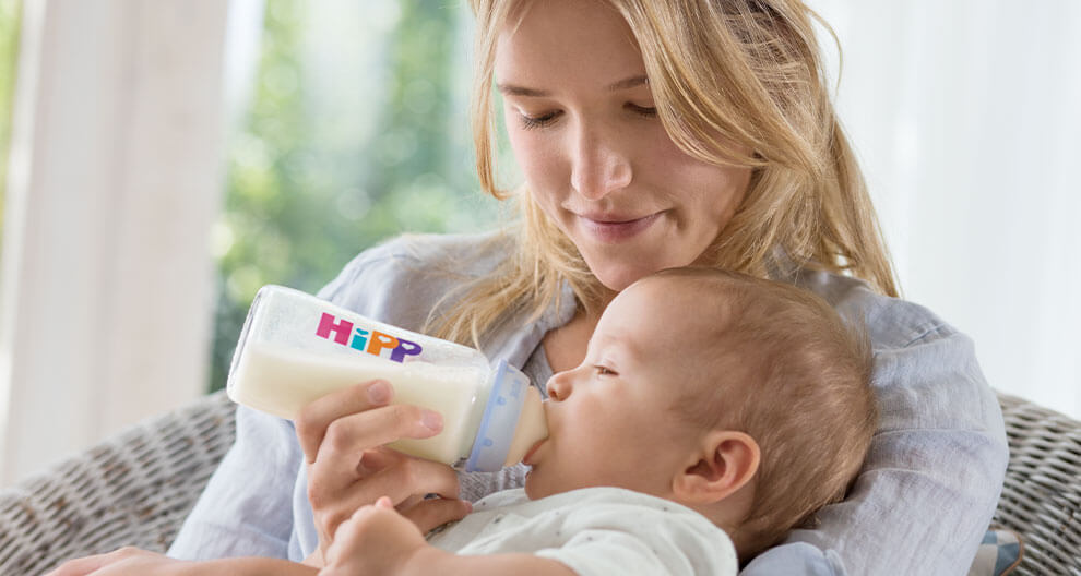 A woman feeds a baby with a Hipp bottle.