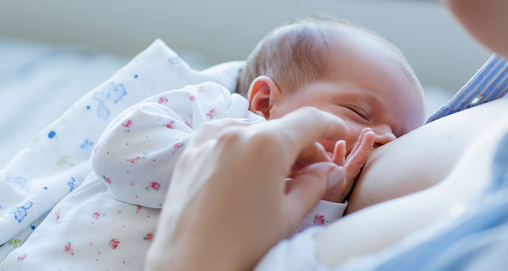 A close-up of a newborn baby being fed by a caregiver.
