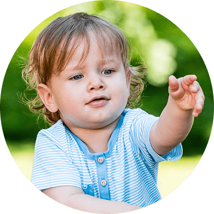 A toddler in a striped shirt is pointing forward.