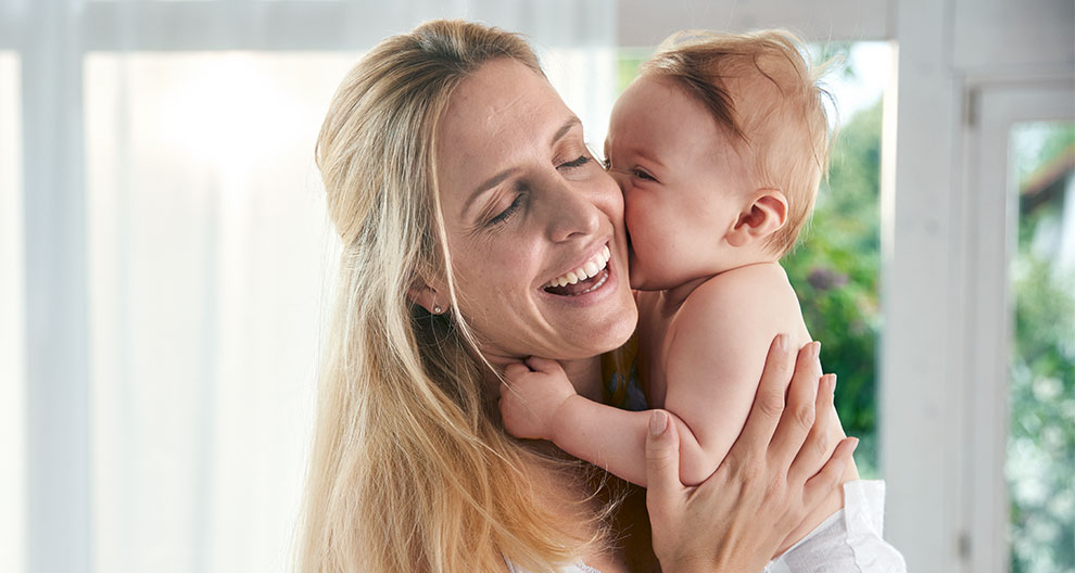 A woman lovingly holds a baby.