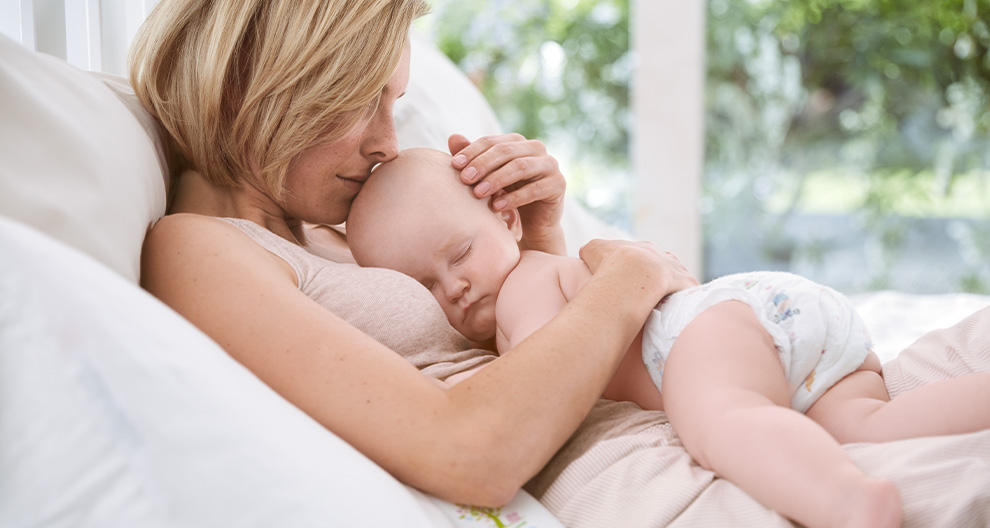 A woman is holding a sleeping baby.
