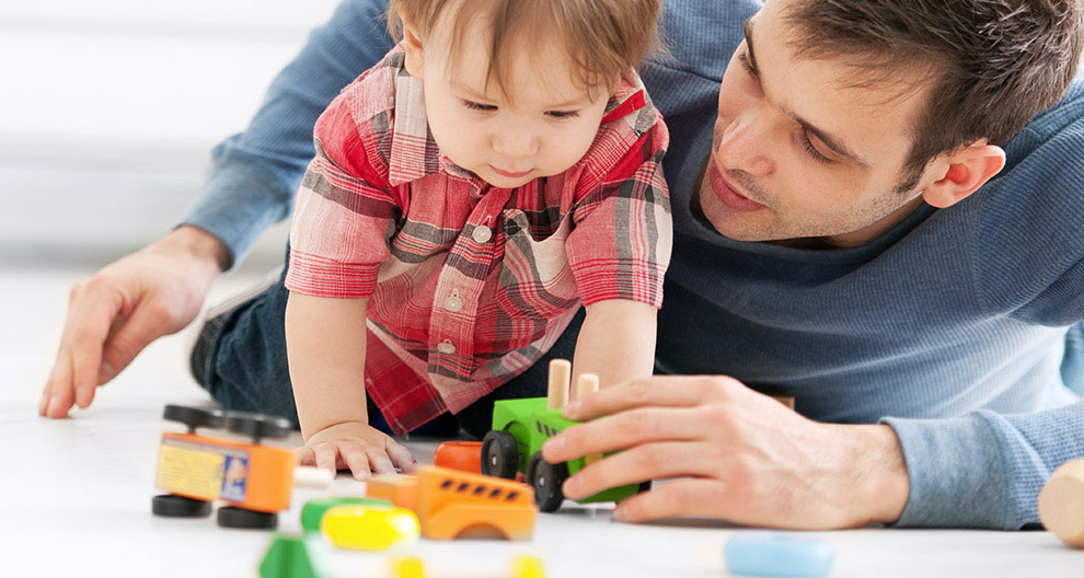 A man and a child play with toys on the floor.