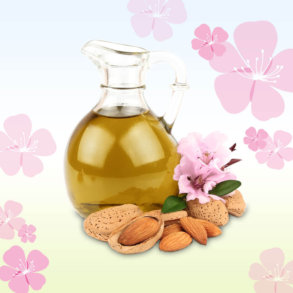 A jug of almond oil surrounded by almond nuts and flowers.